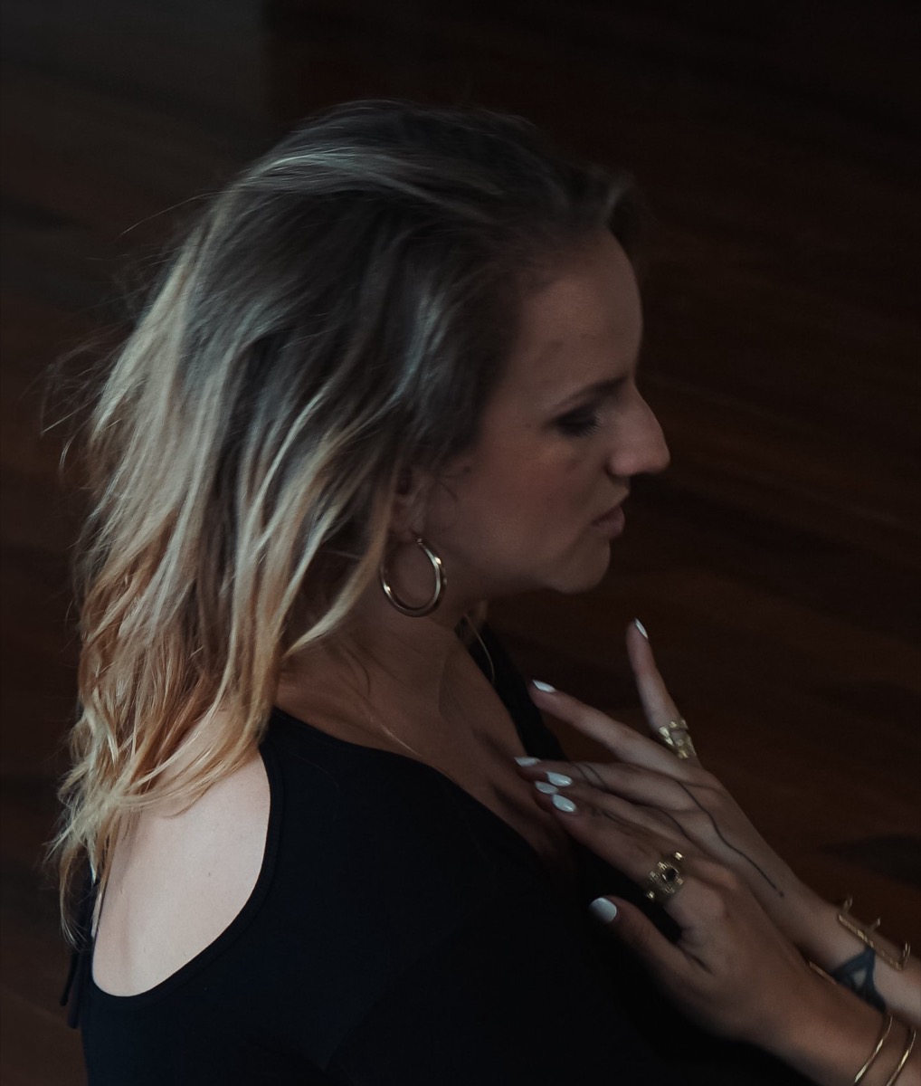 Amanda in profile, eyes lowered, in warm low light