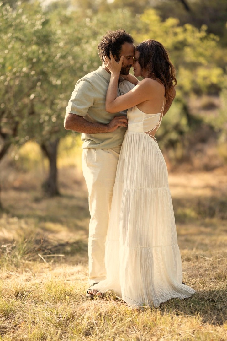 A couple embracing forehead to forehead in an olive grove