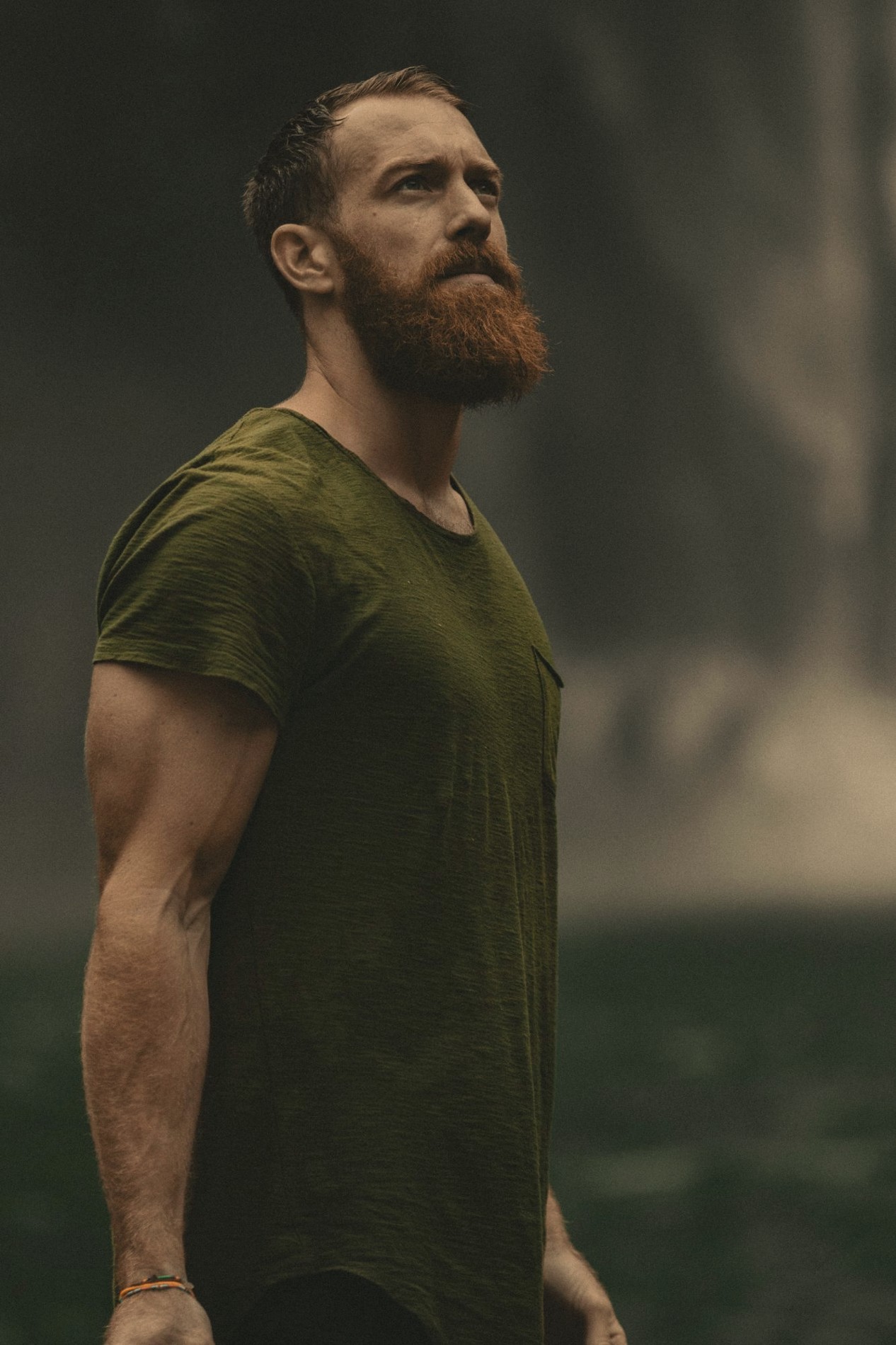 A bearded man in a green t-shirt looking up