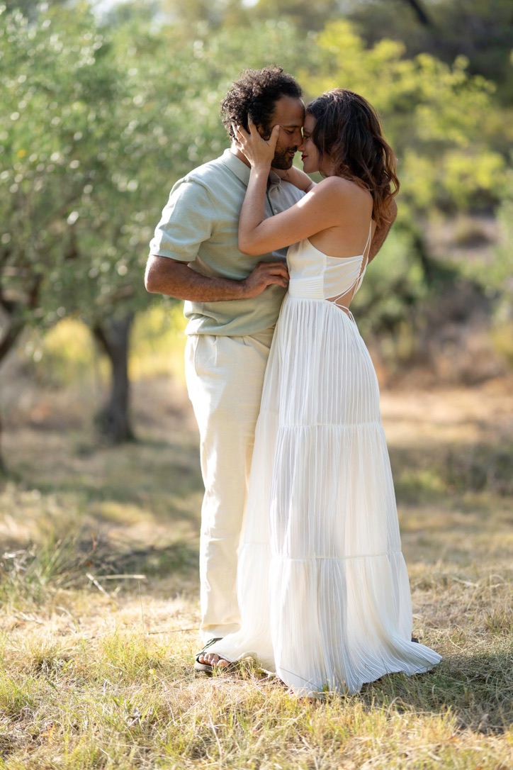 A couple embracing forehead to forehead in an olive grove